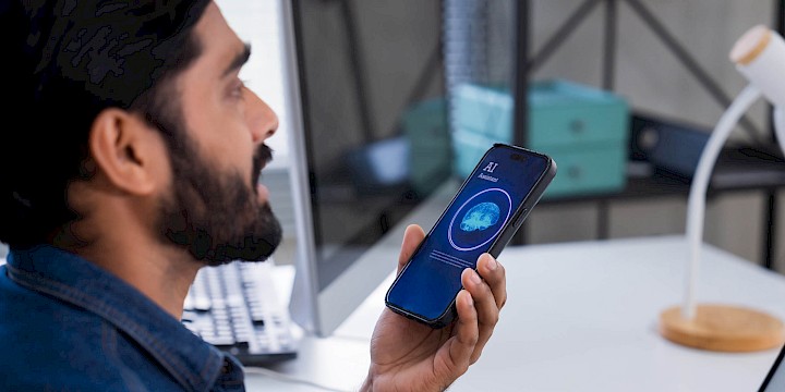 Mann, der mit KI auf Handy spricht, zur Veranschaulichung von KI im Büro