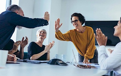 Mitarbeiter geben sich High Five im Meeting