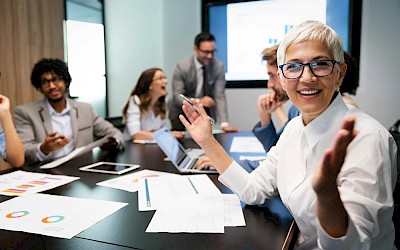 Gestikulierende Frau am Meetingtisch